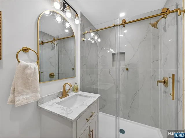 a bathroom with a sink vanity granite tub shower and mirror