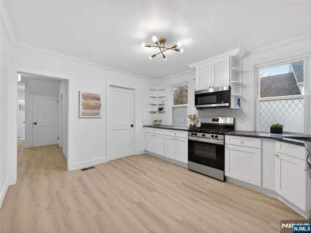 a kitchen with stainless steel appliances a stove top oven a sink dishwasher and a refrigerator with wooden floor