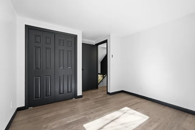 a view of an empty room with wooden floor and stairs
