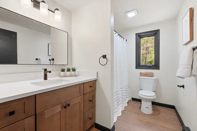 a view of an empty room with wooden floor and windows