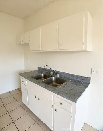 a kitchen with granite countertop white cabinets and a sink