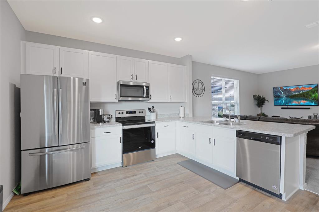 813 Williams Way Van Alstyne, TX 75495 - Photo 14 of 27 a kitchen with white cabinets and stainless steel appliances