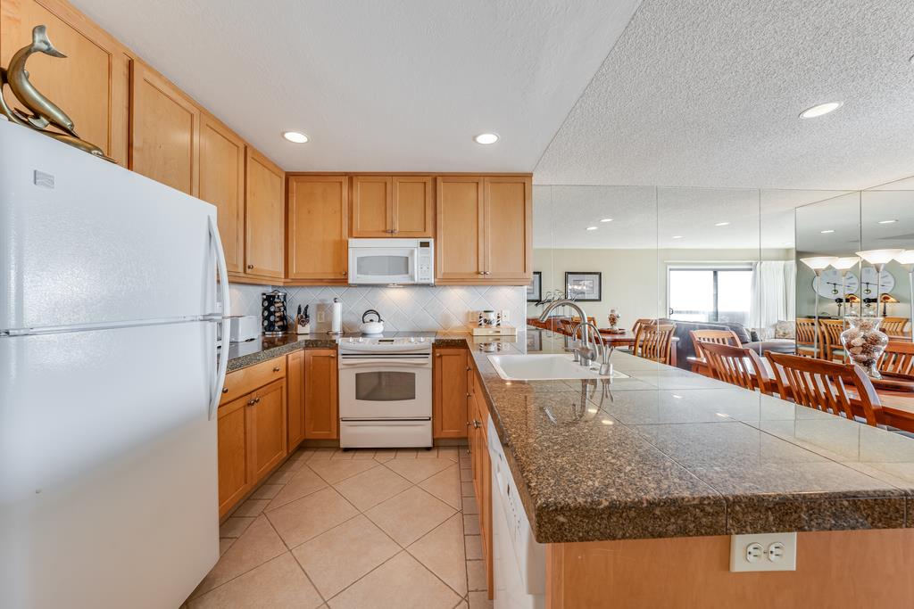 101 Shell Road, Unit 290 Watsonville, CA 95076 - Photo 12 of 26 a large kitchen with stainless steel appliances granite countertop a refrigerator oven a sink a dining table and chairs with wooden floor