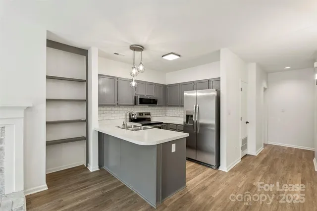 a kitchen with a refrigerator a sink and wooden floor