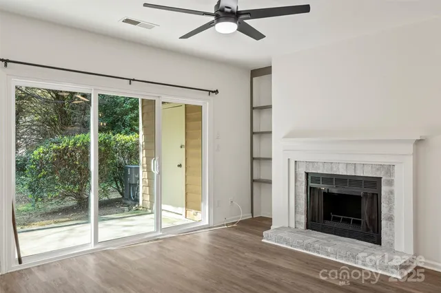 a view of an empty room with floor fan and windows