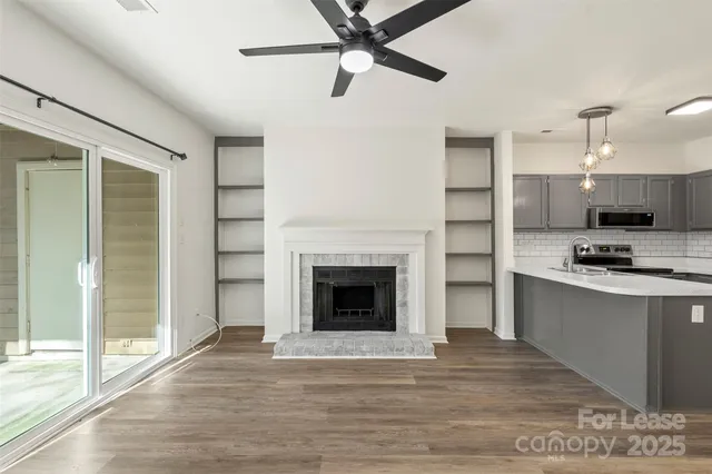a living room with stainless steel appliances granite countertop a fireplace and a ceiling fan