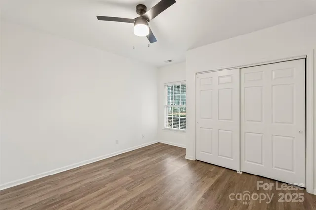 an empty room with wooden floor cabinet and windows