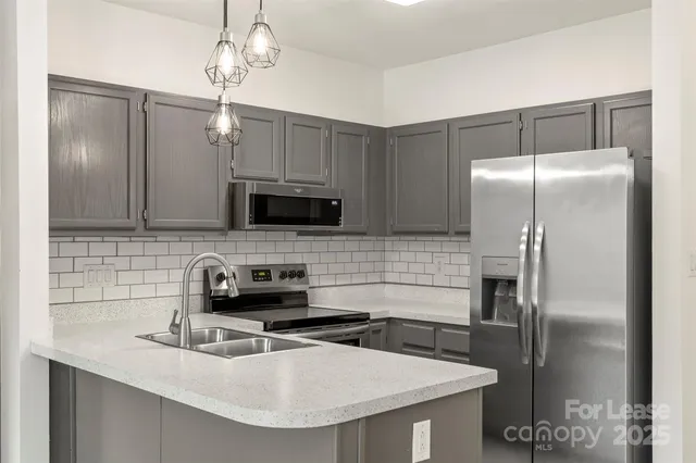 a kitchen with stainless steel appliances granite countertop a sink a microwave a refrigerator and wooden cabinets