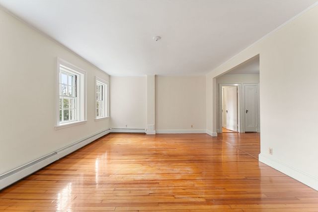 a view of an empty room with window and wooden floor