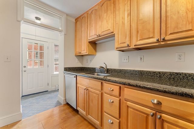 a kitchen with granite countertop white cabinets stainless steel appliances a sink and wooden floor