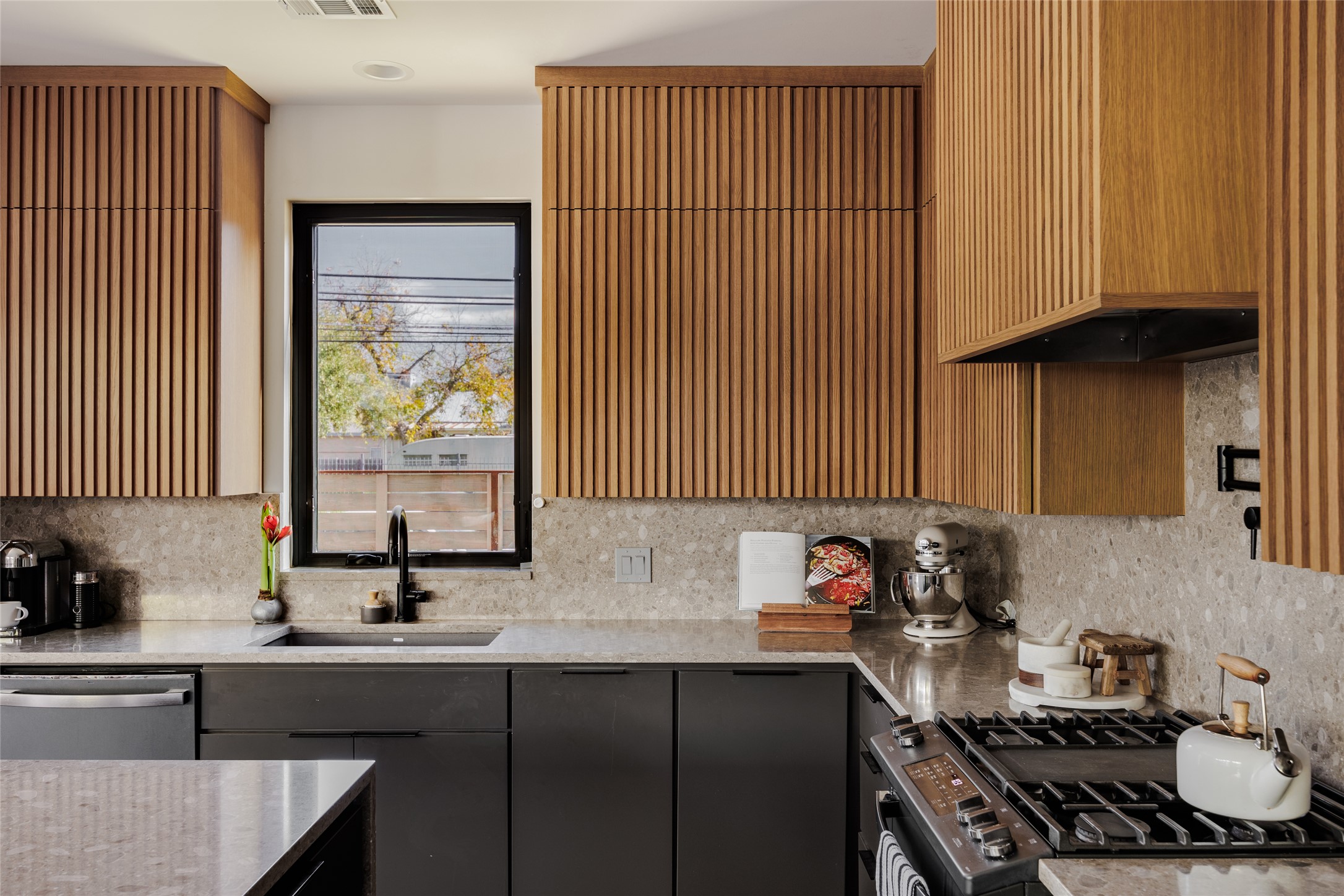 106 Comal Street Austin, TX 78702 - Photo 6 of 40 A contemporary kitchen showcasing wood-slat cabinetry and elegant grey stone countertops.