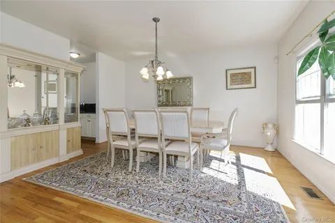 a dining room with wooden floor a chandelier a wooden table and chairs