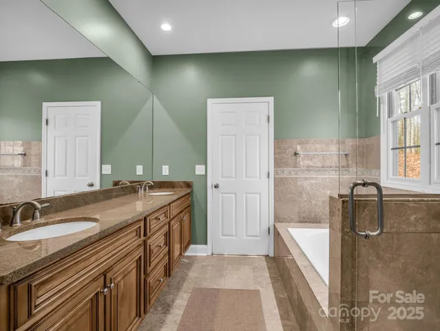 a bathroom with a granite countertop sink a mirror and a bathtub