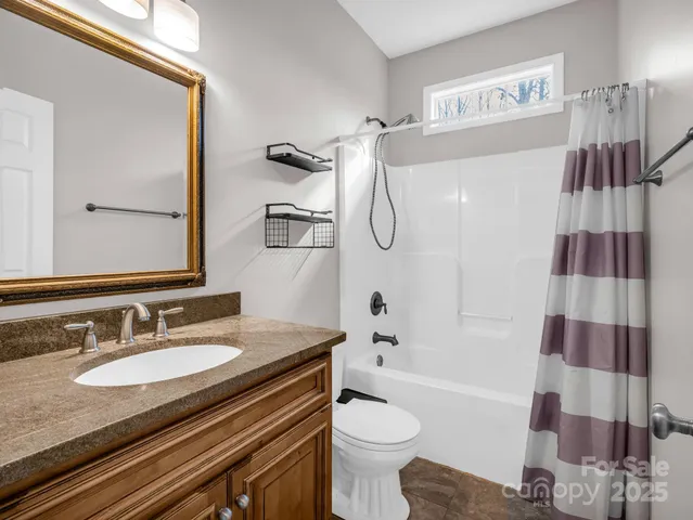 a bathroom with a granite countertop sink toilet a mirror and shower