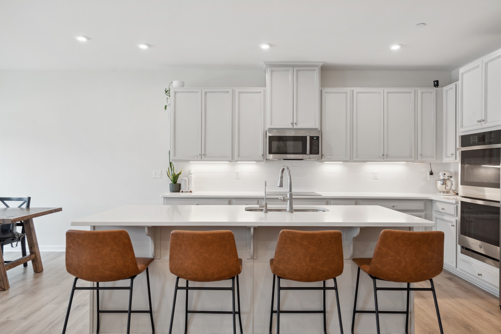 a kitchen with stainless steel appliances granite countertop a white cabinets and chairs