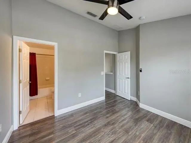 a view of empty room with wooden floor and fan