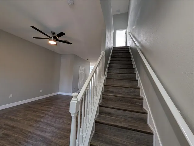 a view of a hallway with wooden floor and a kitchen