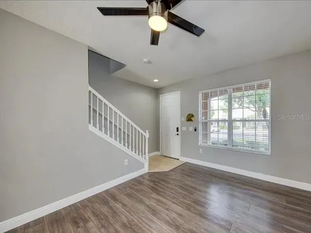 a view of a room with wooden floor staircase and a ceiling fan