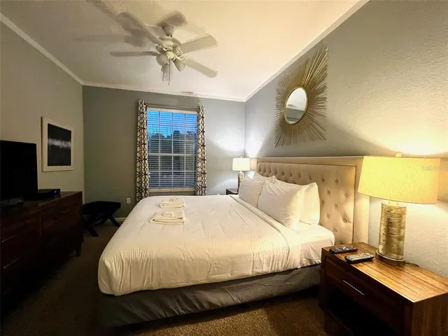 a bed sitting in a bedroom next to a window with a chandelier