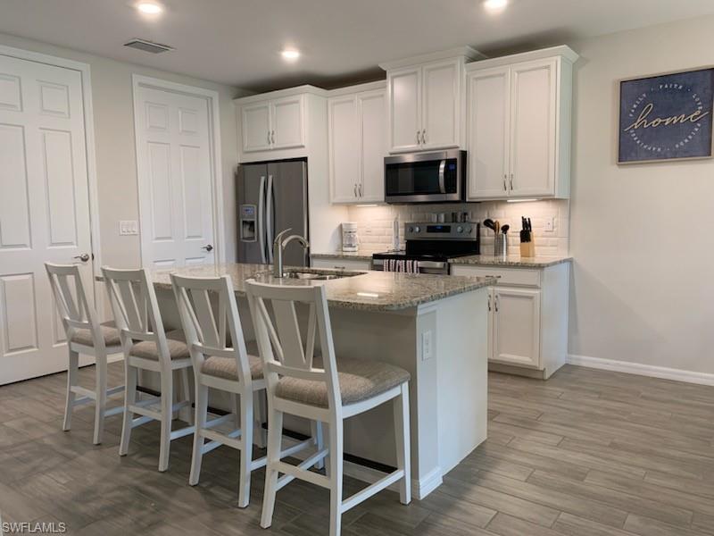 14631 Edgewater Circle Naples, FL 34114 - Photo 5 of 16 a kitchen with stainless steel appliances a microwave a stove a sink dishwasher and white cabinets with wooden floor