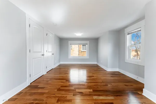 a view of empty room with window and wooden floor