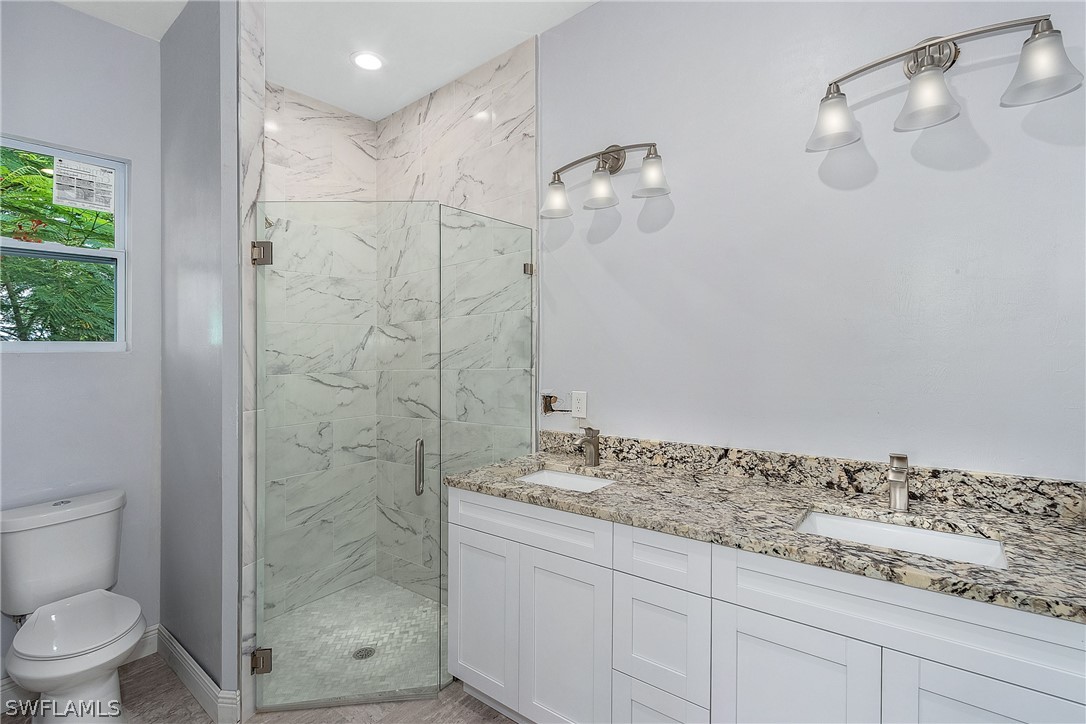 3196 Connecticut Avenue Naples, FL 34112 - Photo 12 of 18 a bathroom with a granite countertop sink a toilet and shower