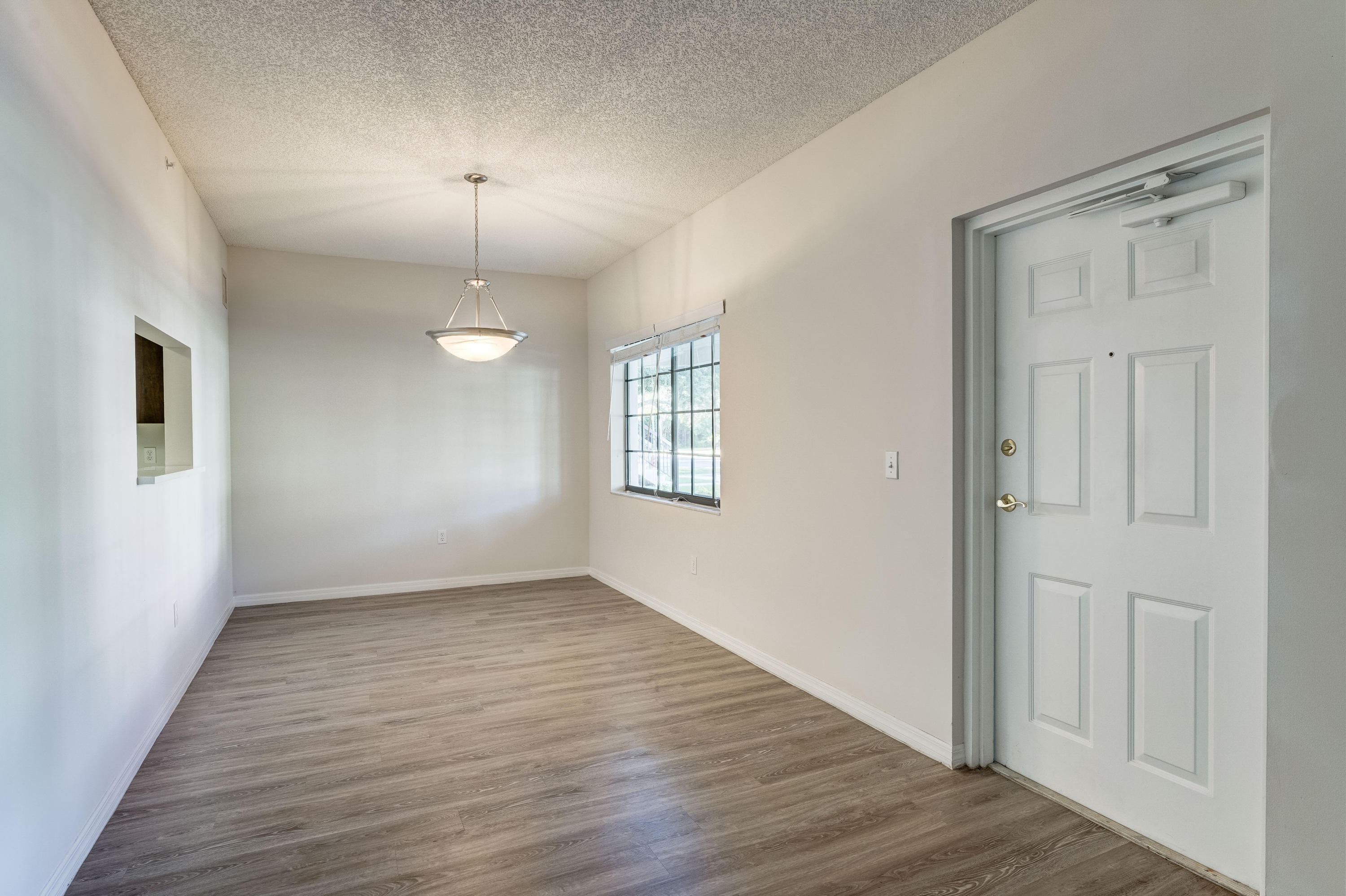 4685 Haverhill Road, Unit B11 West Palm Beach, FL 33417 - Photo 11 of 36 a view of an empty room with wooden floor and a window
