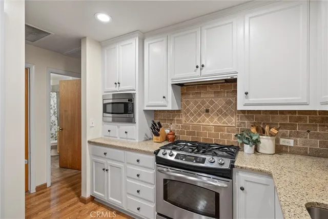 a kitchen with stainless steel appliances granite countertop white cabinets and a stove
