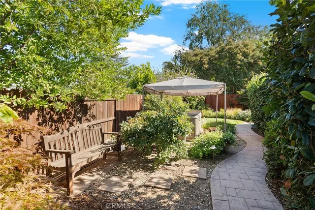 a view of a patio with table and chairs under an umbrella with large trees