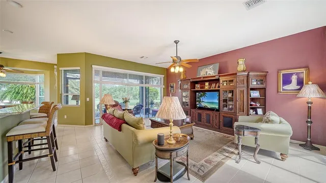 a living room with furniture a flat screen tv and floor to ceiling windows