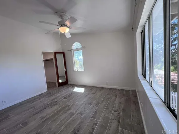 an empty room with wooden floor mirror and window