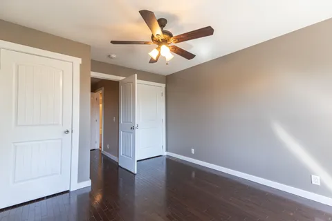 an empty room with wooden floor fan and windows