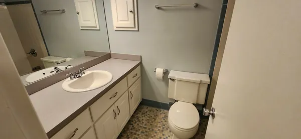 a bathroom with a granite countertop toilet sink and mirror
