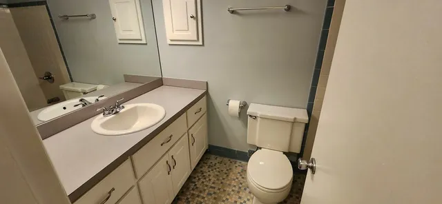 a bathroom with a granite countertop toilet sink and mirror
