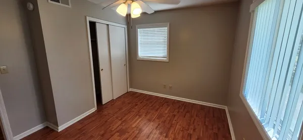 an empty room with wooden floor and windows