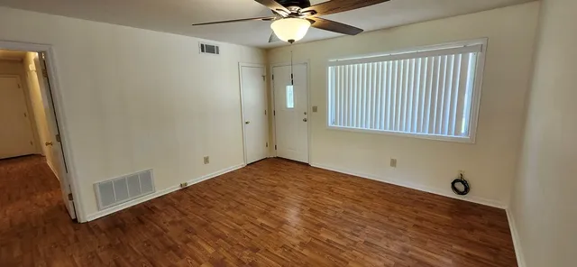a view of an empty room with wooden floor and a window