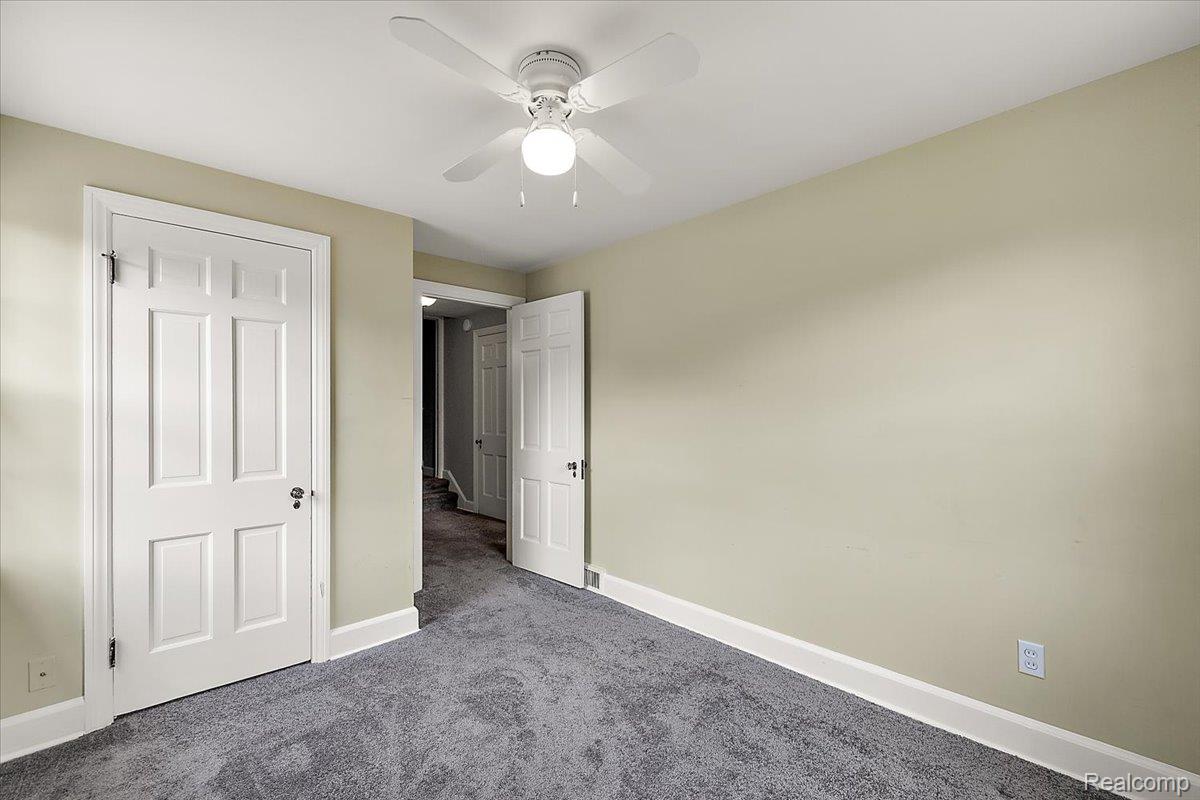 1051 Devonshire Road Grosse Pointe, MI 48230 - Photo 41 of 99 Neutral-toned room featuring a ceiling fan with integrated lighting, textured gray carpeting, and white baseboards