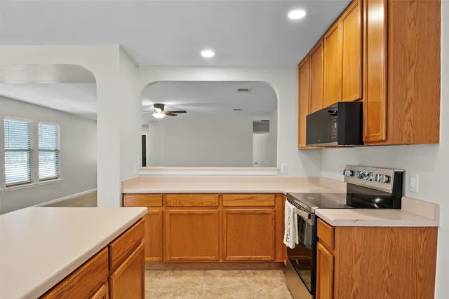 a kitchen with stainless steel appliances granite countertop white cabinets and a window