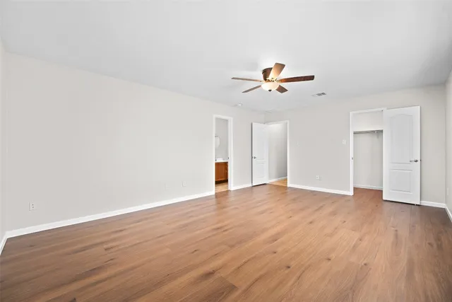 a view of an empty room with a window and a ceiling fan