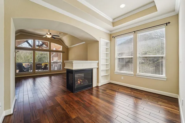 a view of an empty room with window wooden floor and a ceiling fan