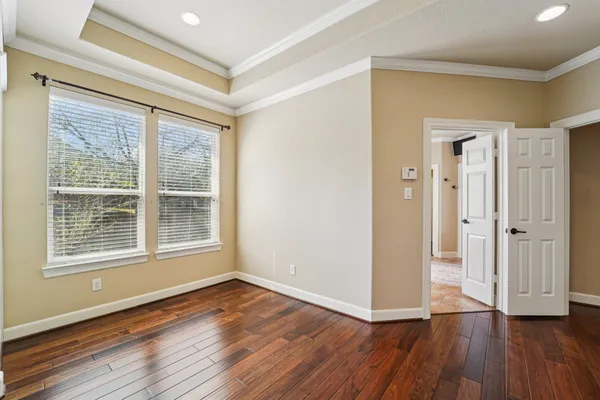 an empty room with wooden floor a fireplace a ceiling fan and windows
