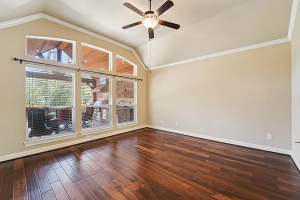 an empty room with wooden floor fireplace and windows
