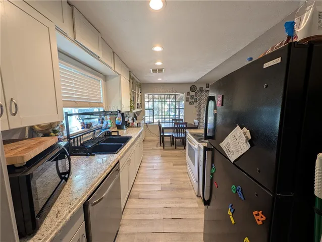 a kitchen with stainless steel appliances granite countertop a sink a stove and a refrigerator