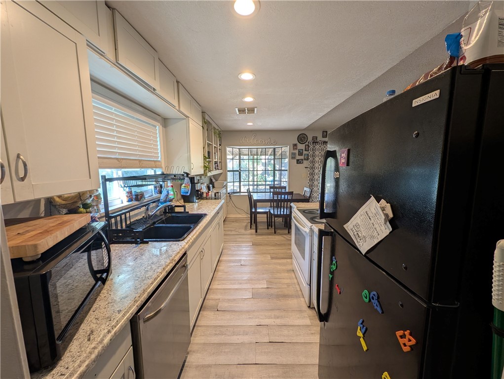 1980 Jocelyn Road Aransas Pass, TX 78336 - Photo 7 of 14 a kitchen with stainless steel appliances granite countertop a sink a stove and a refrigerator