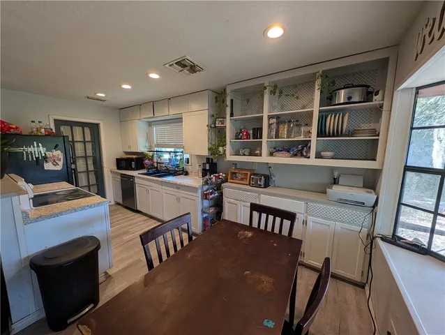 a kitchen with stainless steel appliances granite countertop a refrigerator a stove a sink a dining table and chairs with wooden floor