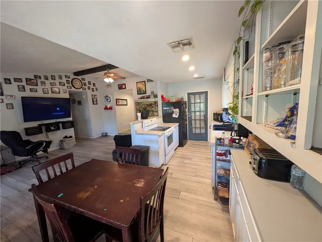 a living room with stainless steel appliances furniture a rug and a kitchen view