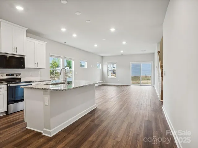 a open kitchen with kitchen island a sink dishwasher stove and wooden floor