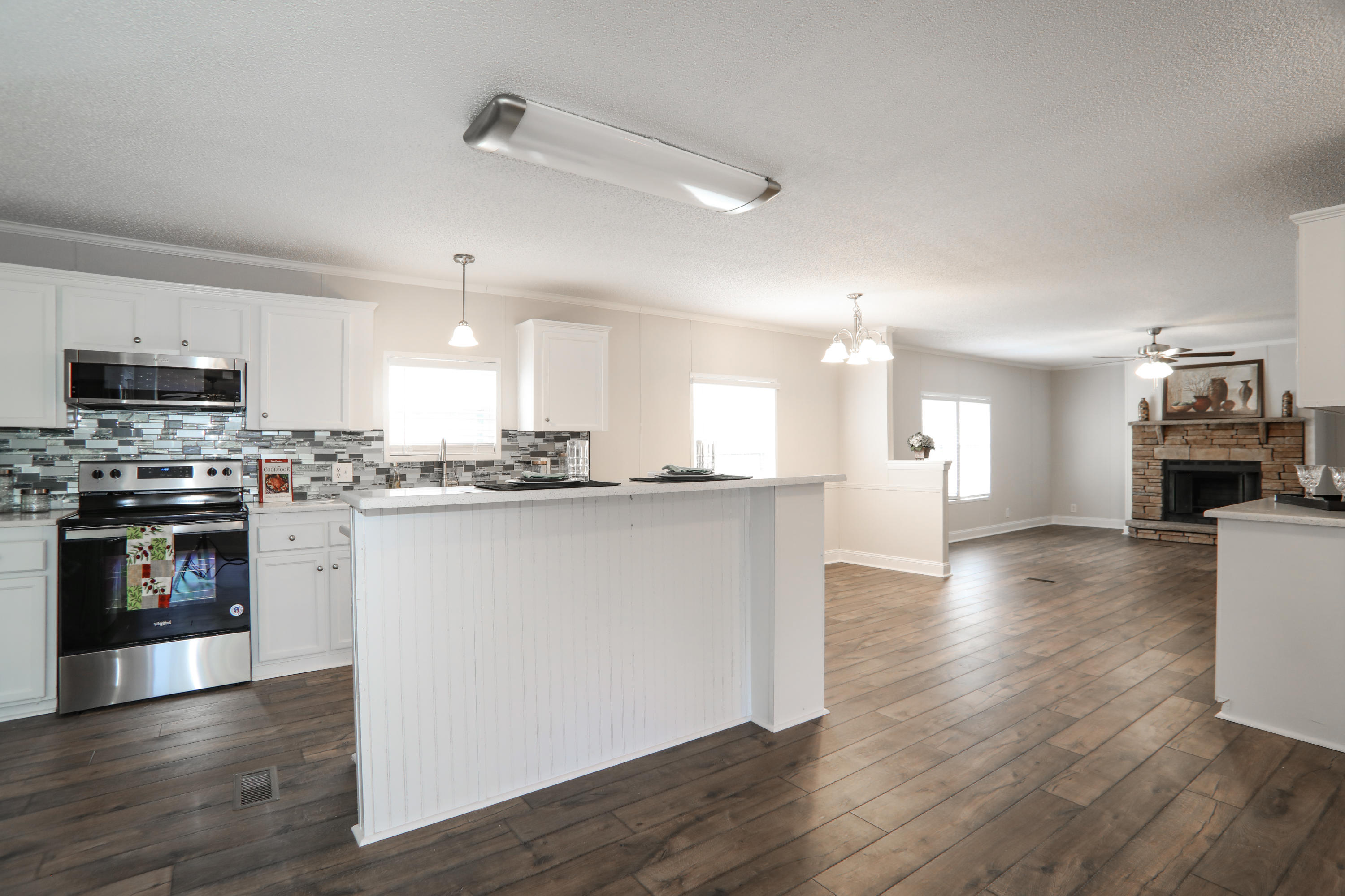 a kitchen with stainless steel appliances granite countertop a stove top oven a sink dishwasher and a refrigerator with wooden floor