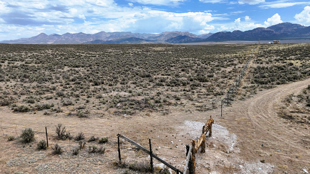 123 East Tbd 5000 Road North Panguitch, UT 84759 - Photo 48 of 54 Expansive undeveloped land with a distant mountain backdrop, featuring natural scrub brush, a partial wire fence, and a dirt path
