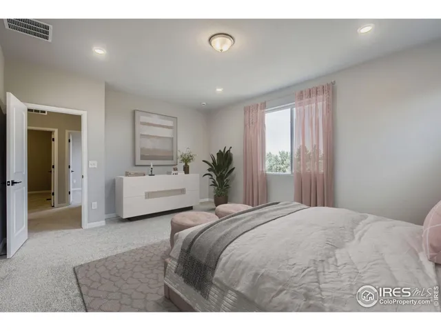 a bedroom with a white bed and a large window